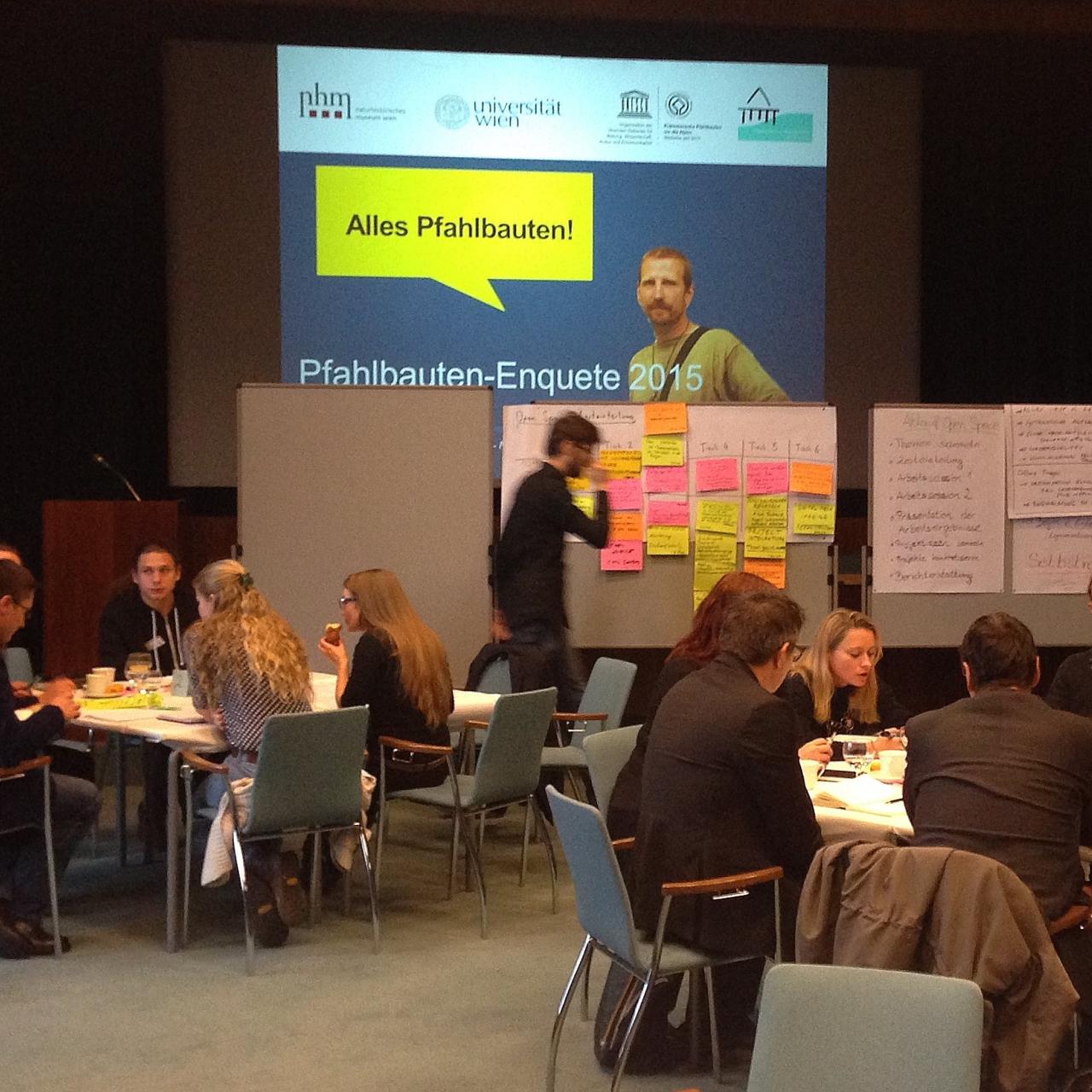 Mehrere Arbeitsgruppen sitzen an getrennten Tischen und Visionboards