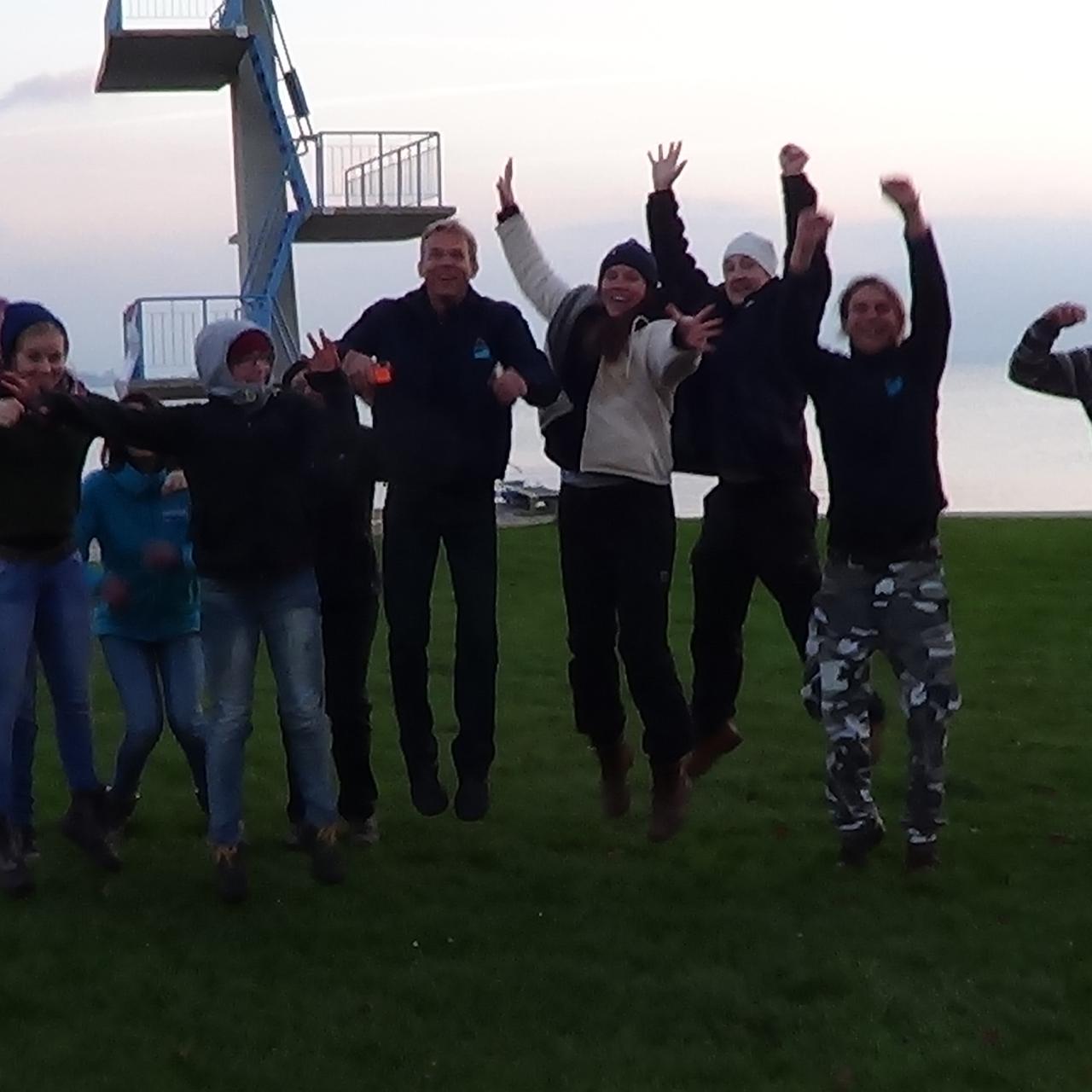 Eine Menschengruppe vor dem Sprungturm in Seewalchen wurde im Sprung fotografiert